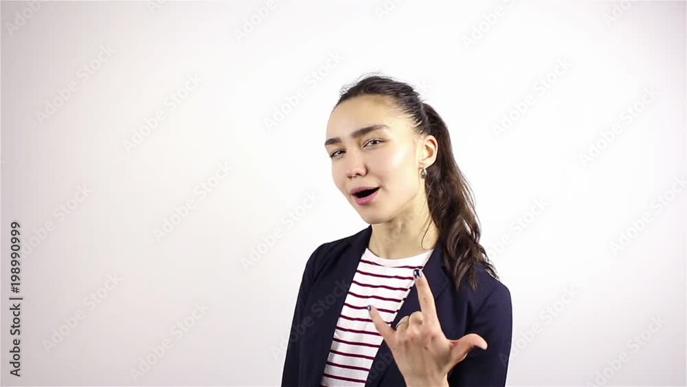 A beautiful young girl gestures by shows heavy metal gesture. A beautiful young girl gestures by shows heavy metal gesture.
