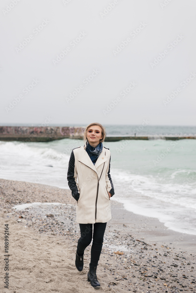 blonde is walking along the beach and smiling blonde is walking along the beach and smiling
