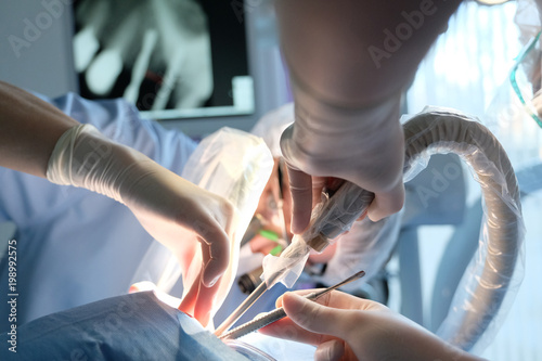 The hands of the dentist and the assistant in protective gloves with the instrument in the treatment of the patient