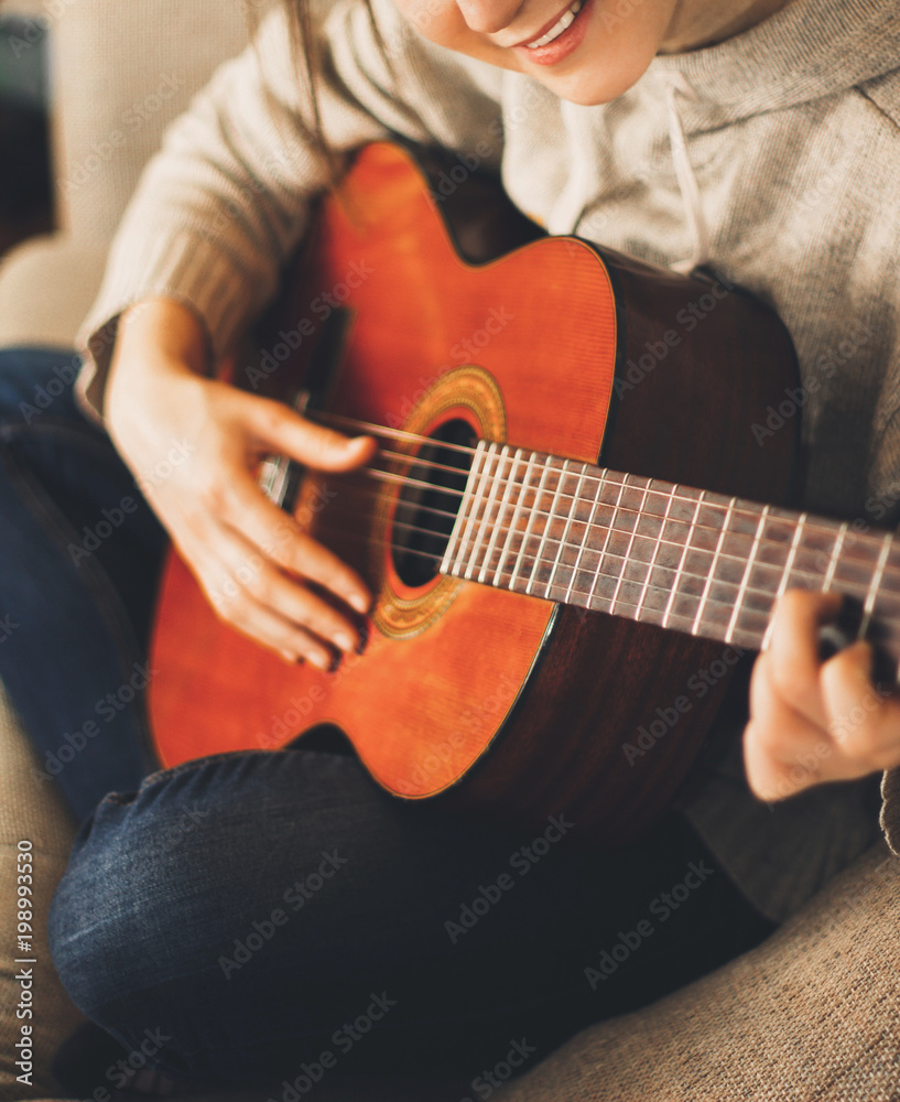 Woman musician playing classical guitar at home