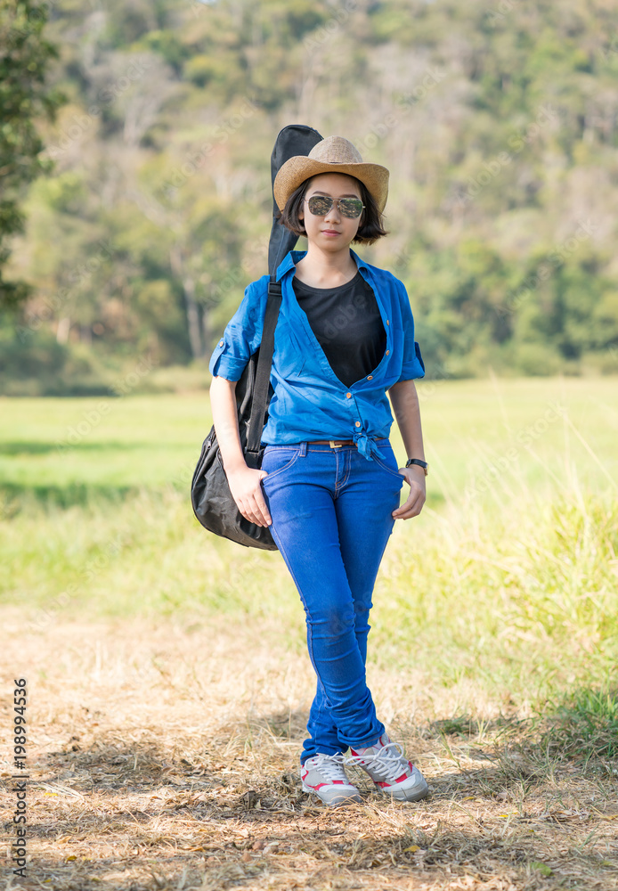 woman wear hat walking and carry her guitar bag woman wear hat walking and carry her guitar bag