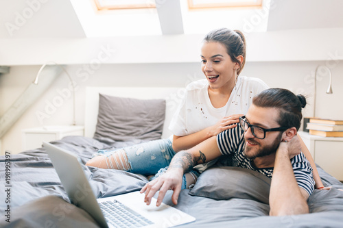 Young couple watching a movie on their laptop in bed 