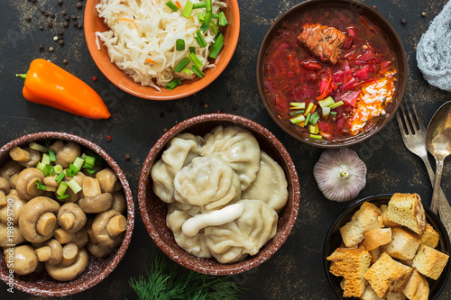 Russian variety of dishes, borsch, dumplings, pickled mushrooms, sauerkraut. Russian food on a rustic background, top view.