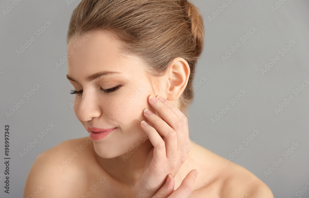 Young woman applying cream onto her skin against color background Young woman applying cream onto her skin against color background