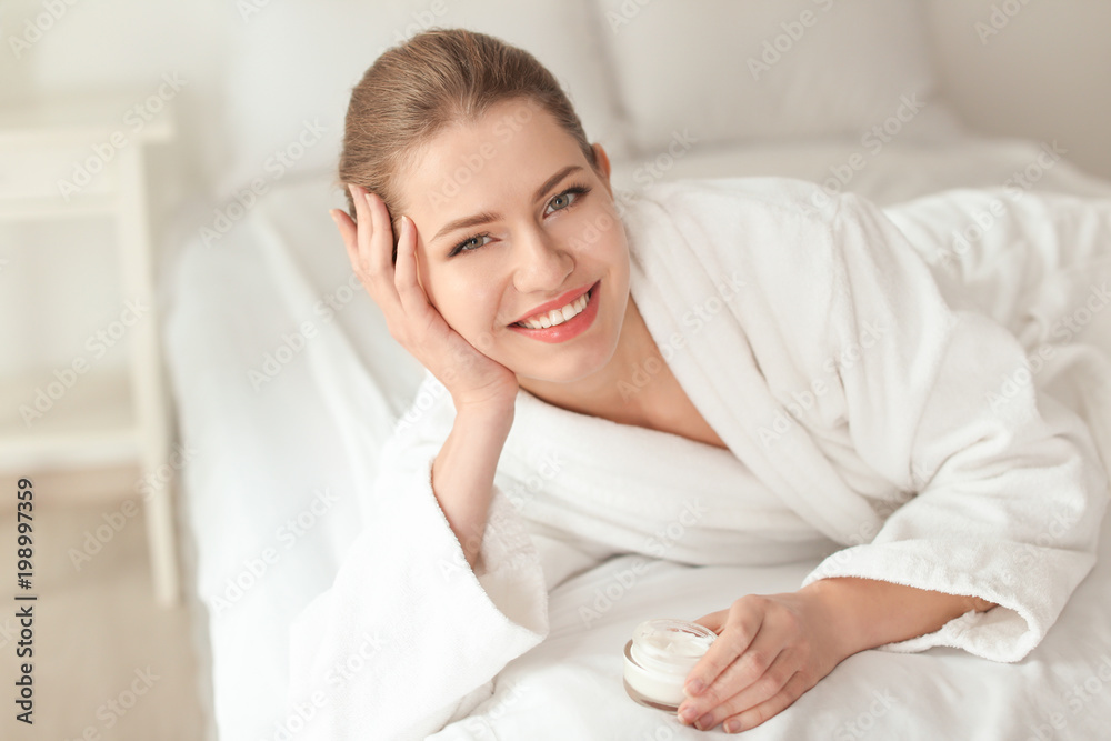 Young woman with jar of hand cream indoors Young woman with jar of hand cream indoors