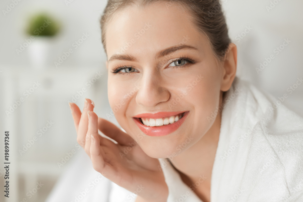 Young woman applying cream onto her skin, closeup Young woman applying cream onto her skin, closeup