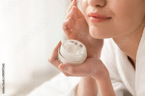 Fototapeta Naklejka Na Ścianę i Meble -  Young woman applying cream onto her skin, closeup