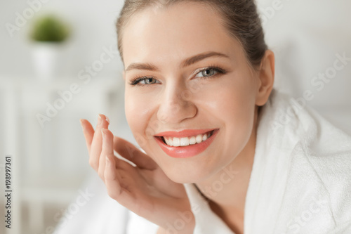 Young woman applying cream ...