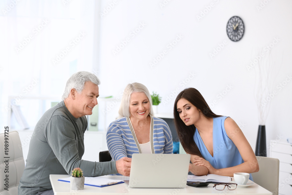 Mature couple discussing pension plan with consultant in office Mature couple discussing pension plan with consultant in office