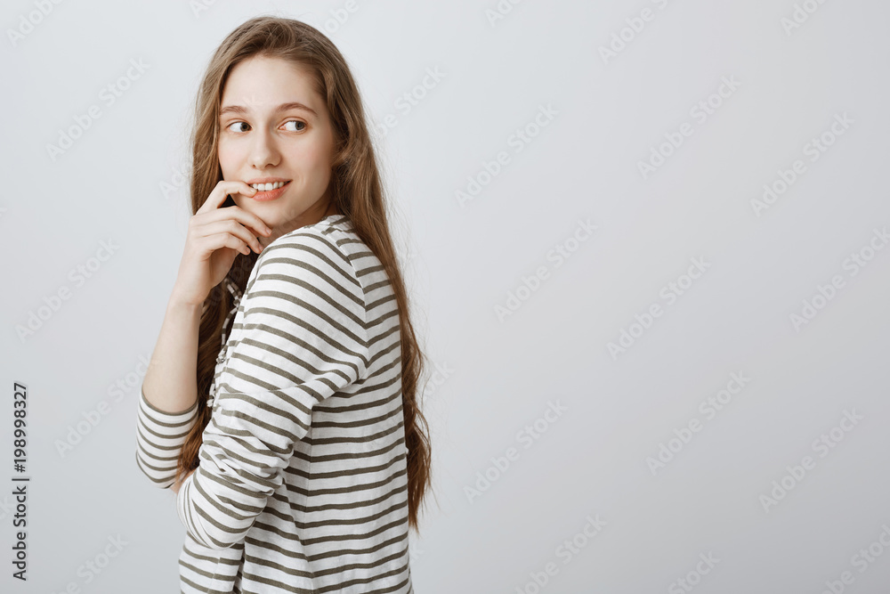 Interesting things happen near copy space. Portrait of curious and intrigued good-looking woman standing in profile, looking behind with flirty smile, having idea or wanting something she sees Interesting things happen near copy space. Portrait of curious and intrigued good-looking woman standing in profile, looking behind with flirty smile, having idea or wanting something she sees