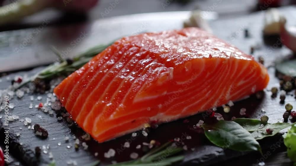 Preparation of salmon steak. Spice and salt sprinkled on a raw piece of salmon. Camera moves around the object. Slow motion 120 fps video.