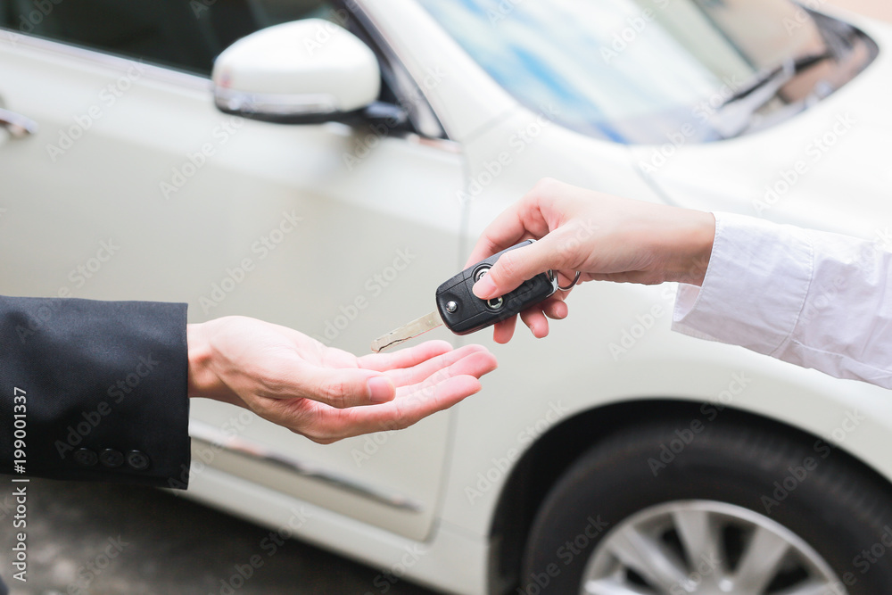Salesman offering car key to a businessman from the car dealer.