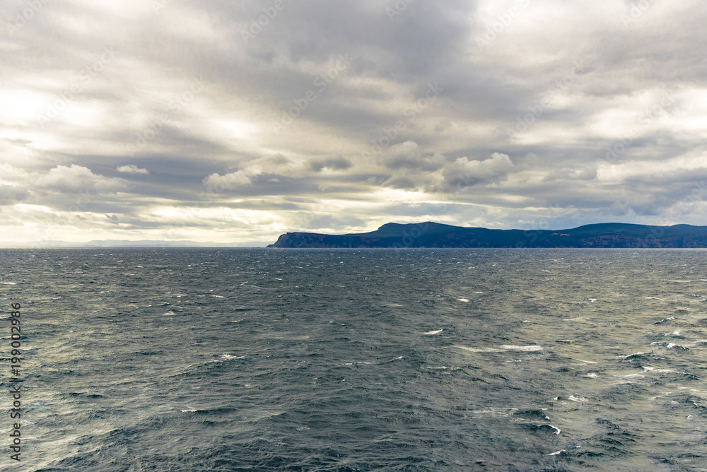 Scenic view of Tasman sea from a boat, cloudy sky in background. Storm Bay is a large bay in the south-east region of Tasmania, Australia.