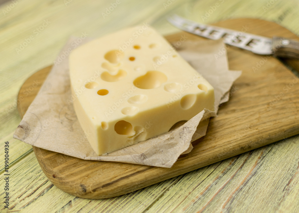 Cheese on cutting board  and knife on wooden background