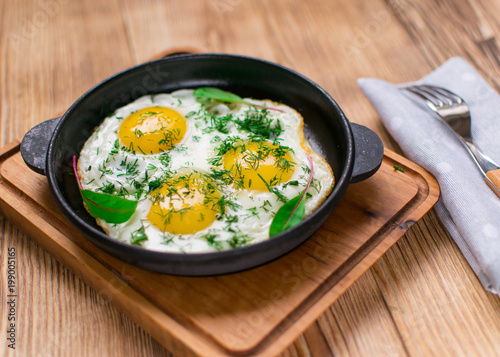 fried eggs in a frying pan and greens.