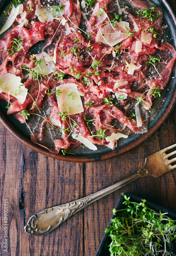 Delicious homemade organic carpaccio with Parmesan cheese, spices and herbs top view