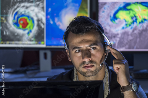 Meteorologist monitoring storms on his computer screens, close up shot photo