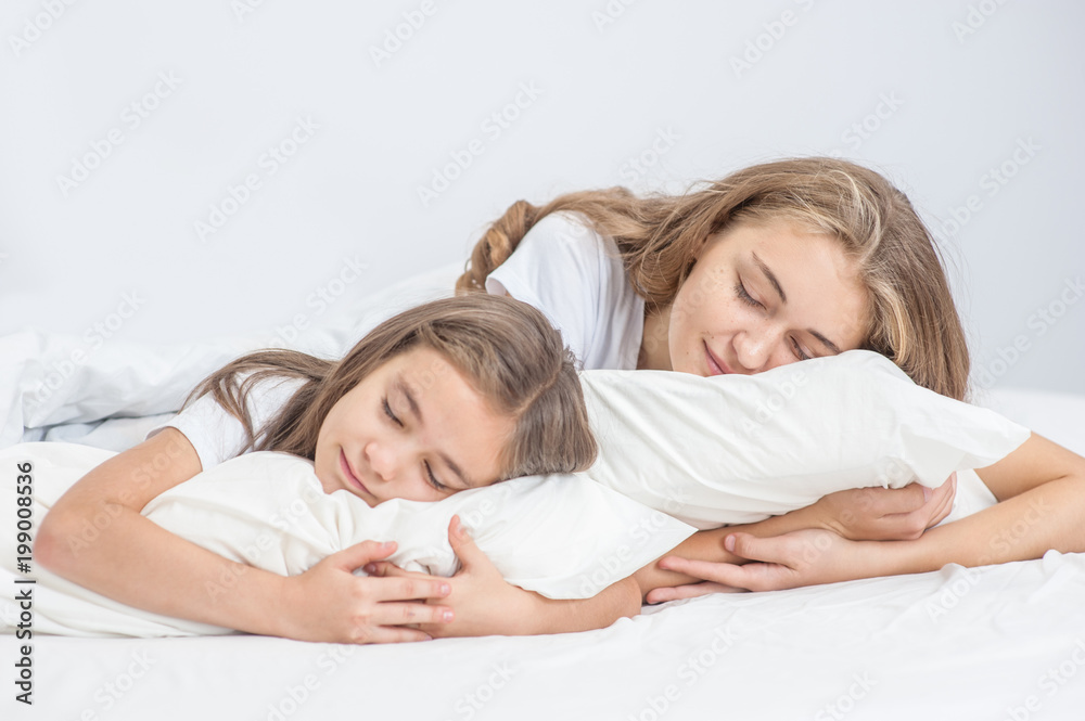 Happy mom and daughter lying together on the pillows Happy mom and daughter lying together on the pillows