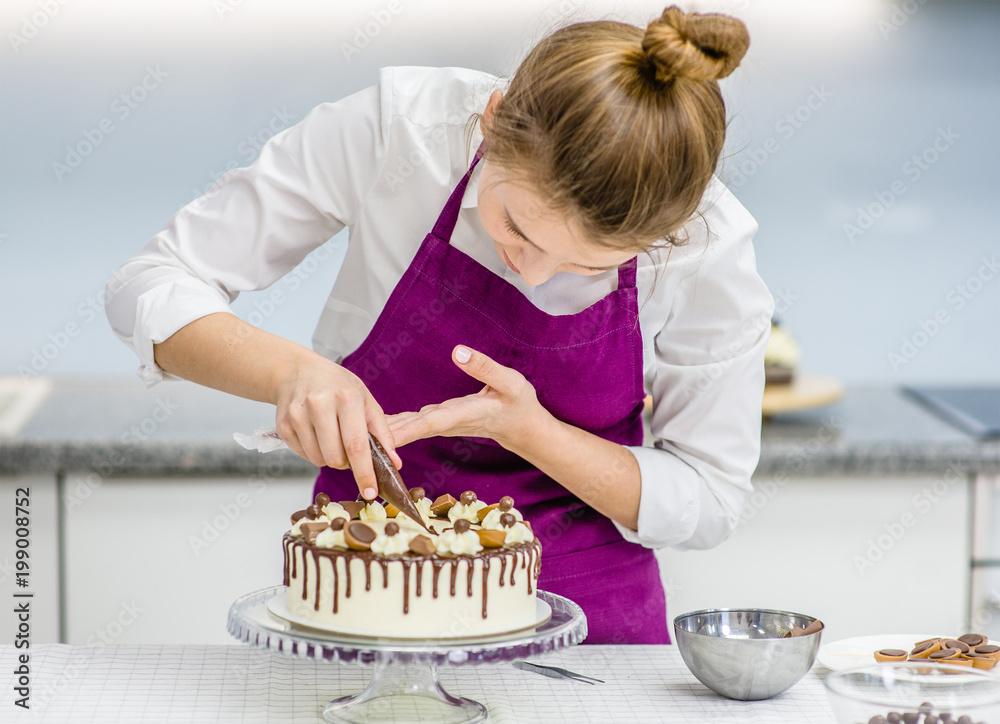 woman decorating chocolate cake in the kitchen