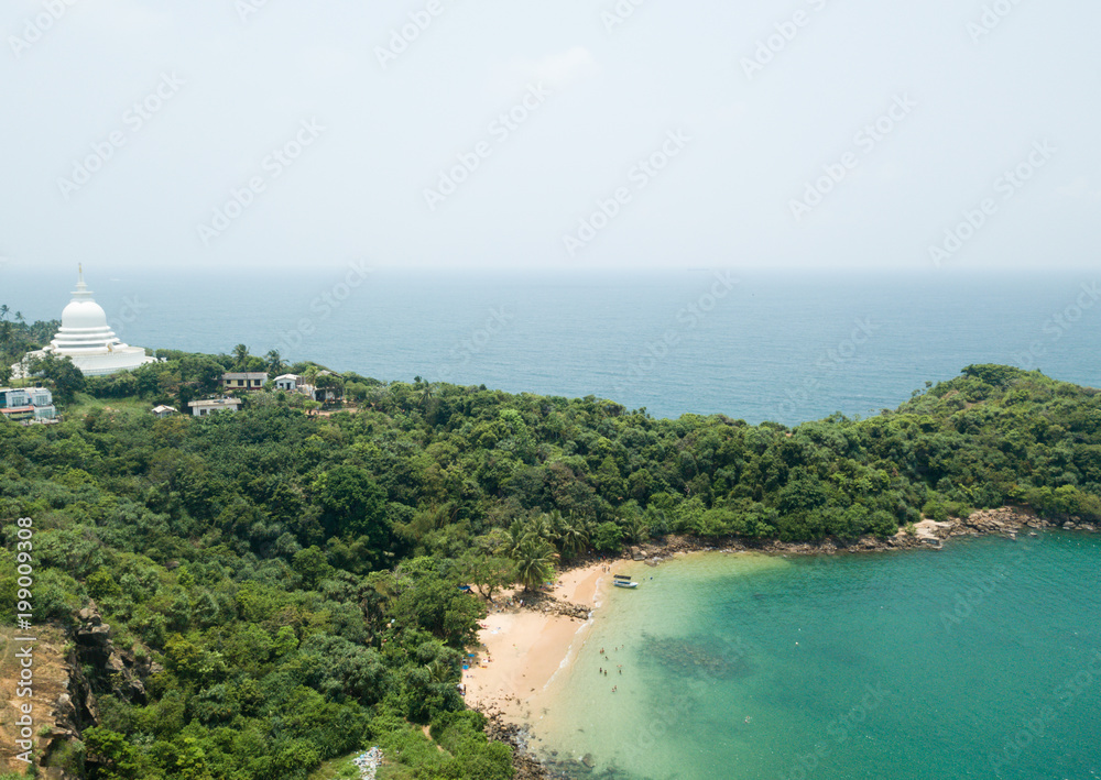 Paradise beach witch turquoise sea water and a big pagoda on top of the mountain. Popular beach in Sri lanka. Asia landscape, aerial view. 