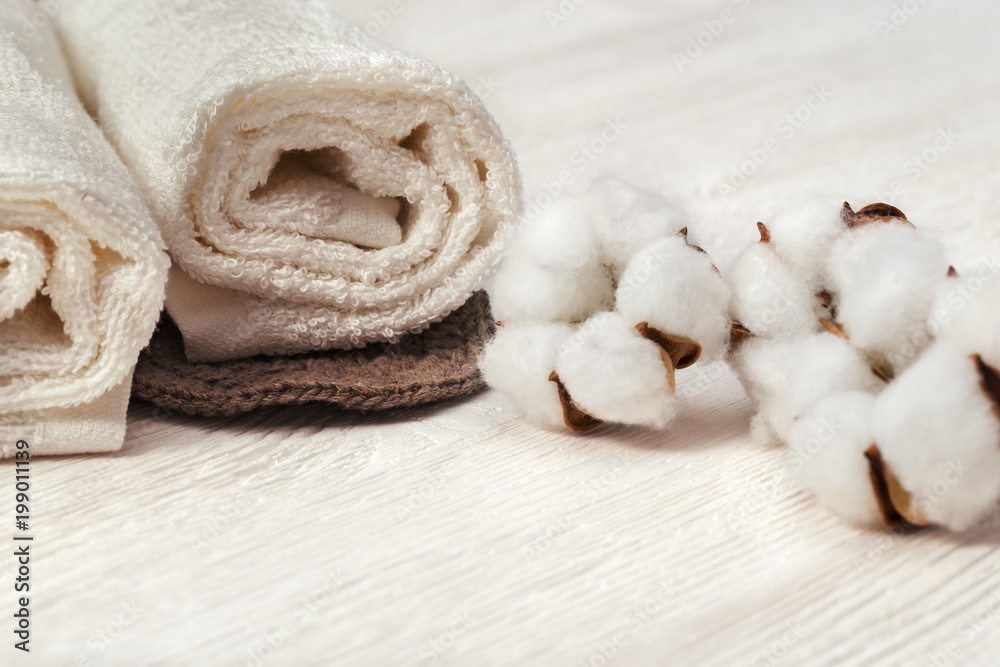 Spa concept. Cotton flower plant and cotton rolled towel on white wooden background with copy space. Toned photo. Spa concept. Cotton flower plant and cotton rolled towel on white wooden background with copy space. Toned photo.