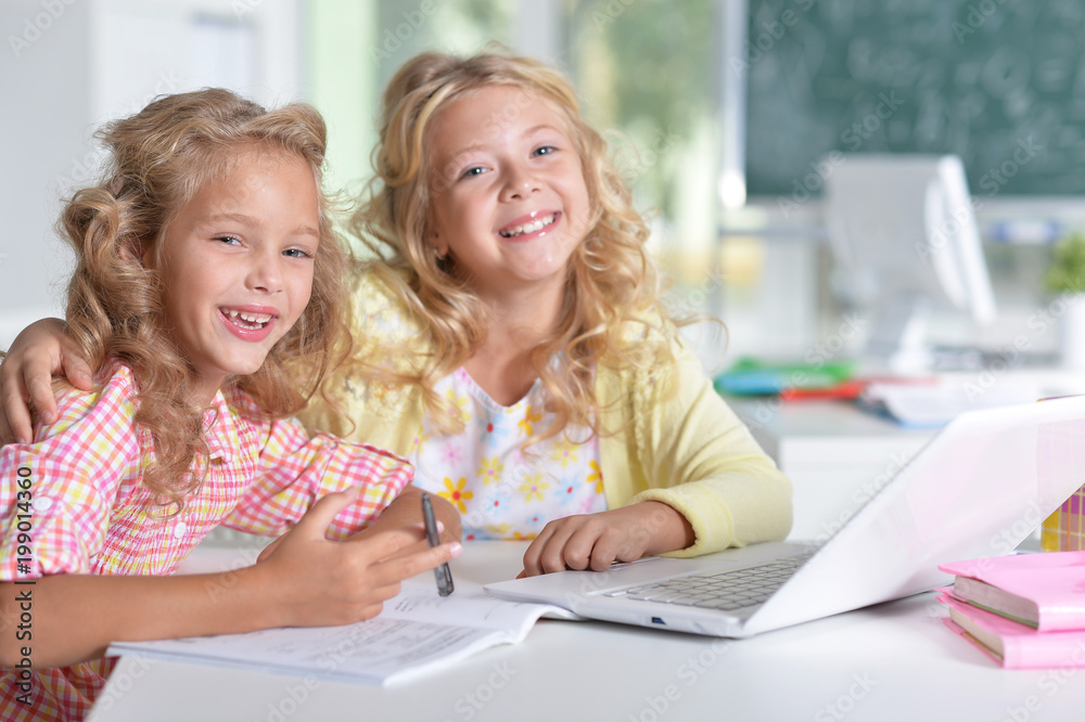 Two girls at class using laptop and writing Two girls at class using laptop and writing