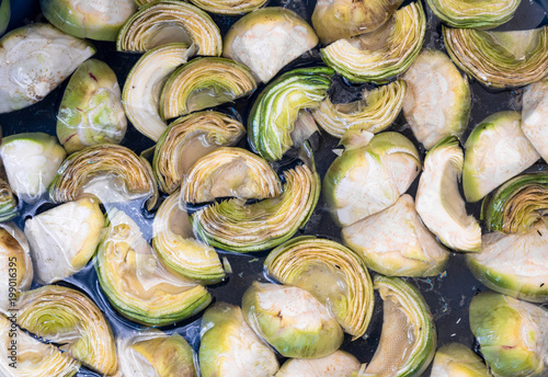 Cut artichokes in water on market stall. Green healthy vegetables.. photo