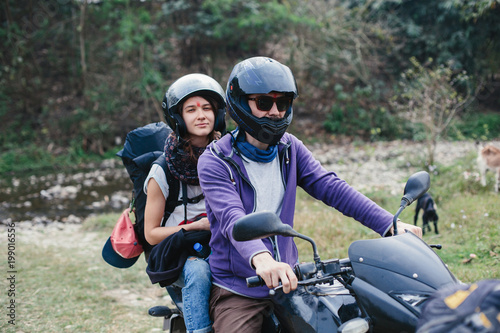 Couple of motor travellers wearing helmets driving motorcikle in mountains