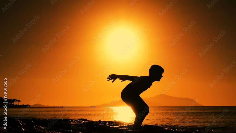 silhouette of boy jumping at sunrise