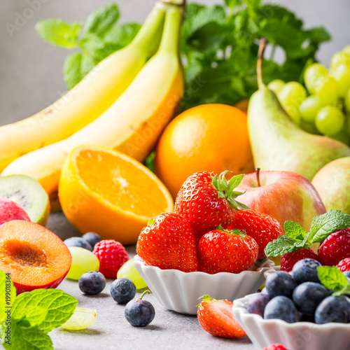 Fresh assorted fruits and berries on light gray background. Colorful clean and healthy eating. Detox food.