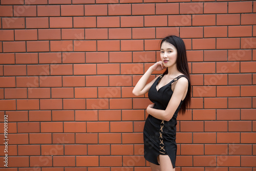 Portrait of beautiful asian chic girl wear black dress pose for take a picture on brick wall,Lifestyle of teen thailand people,Modern woman happy concept