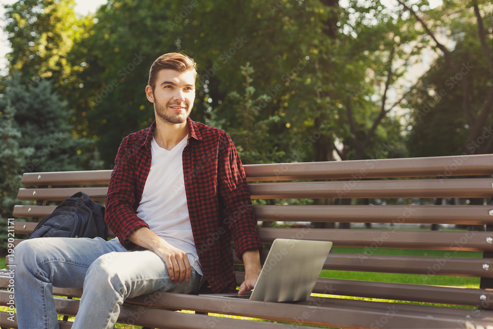 Fototapeta premium A smiling man with laptop outdoors