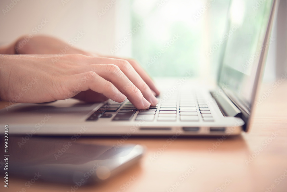 Closeup woman's hands typing on a laptop on a wooden desk. Closeup woman's hands typing on a laptop on a wooden desk.