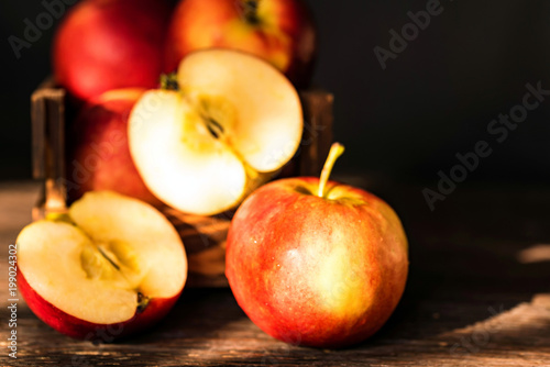 Apples whole and cut in halves on wooden surface
