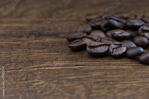 Coffee beans on a dark background and a wooden table. Closeup.