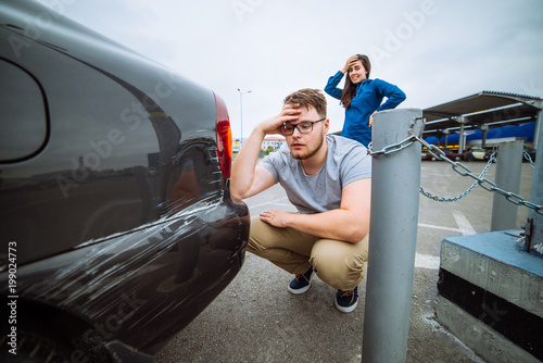 man with sad look on scratched car. woman with sorry look near d photo