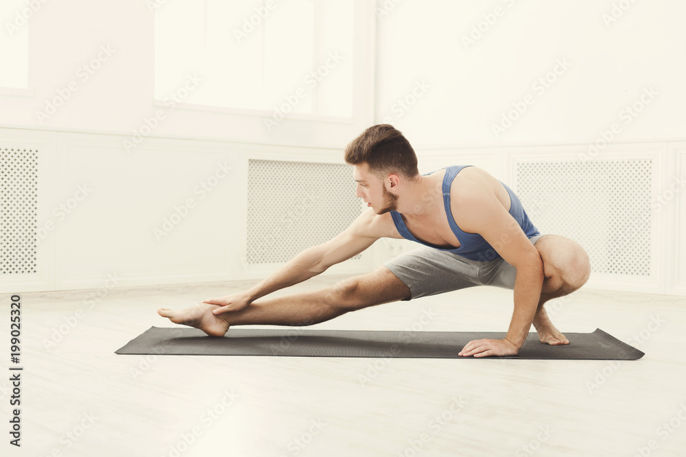 Man stretching at white background indoors