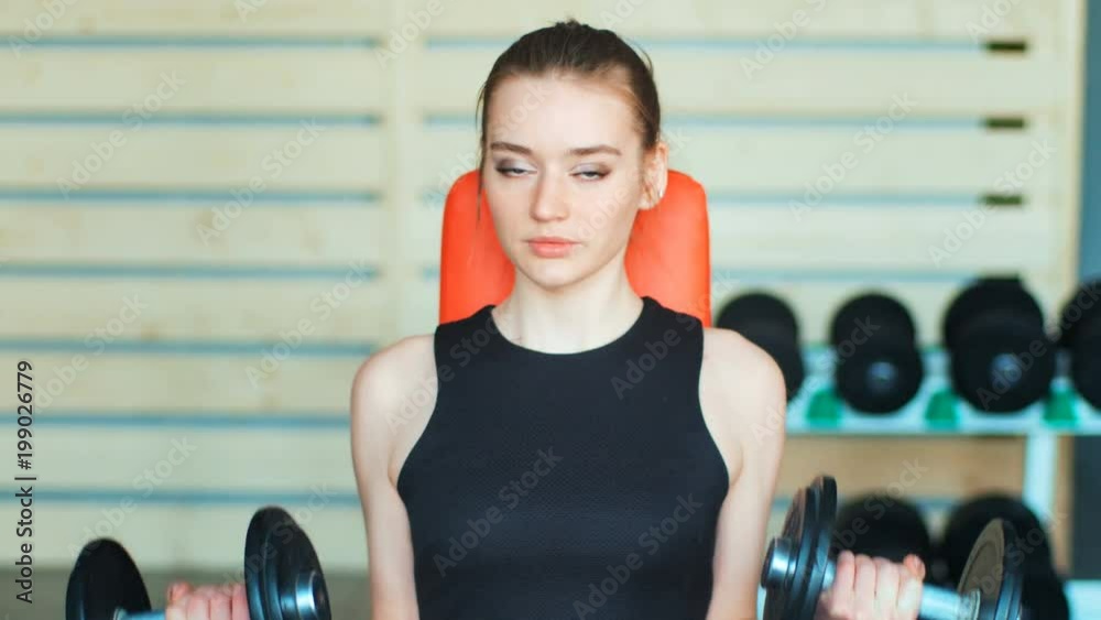 Sporty young woman exercising with dumbbells in the gym Sporty young woman exercising with dumbbells in the gym