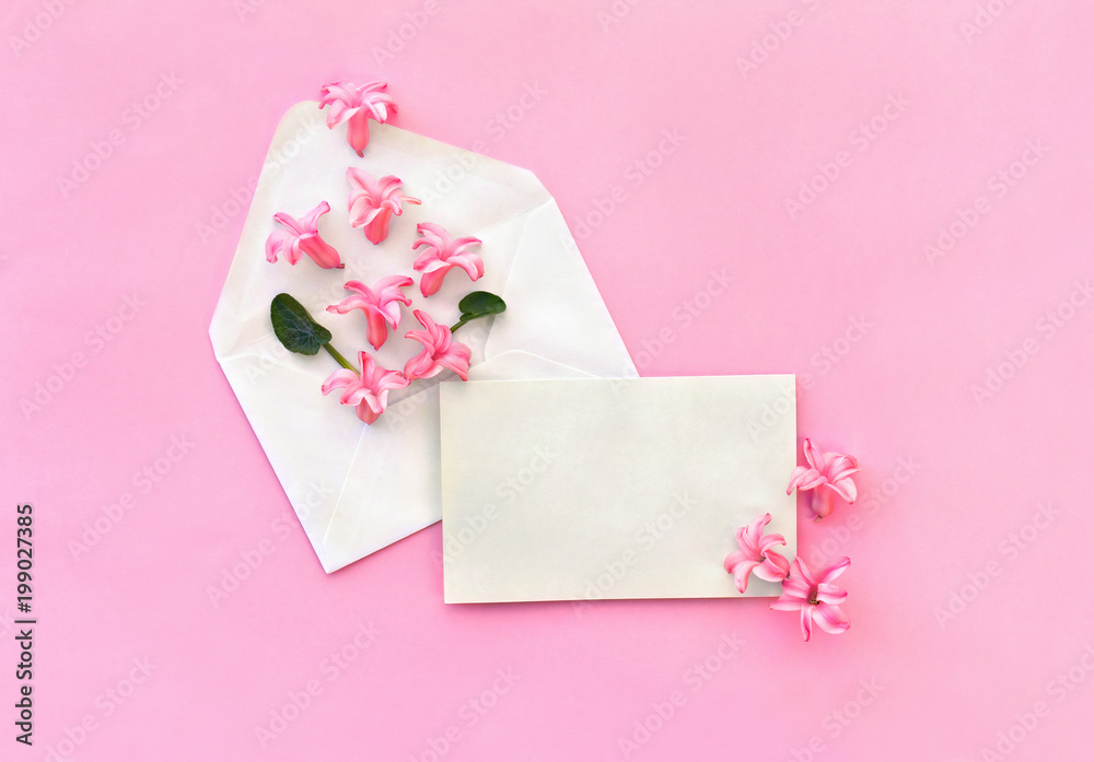 Beautiful flowers pink hyacinth in postal envelope and blank sheet with space for text on a pink paper background. Top view, flat lay