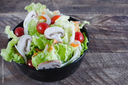 Bowl of salad on rustic wooden background.