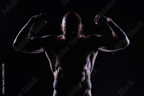 Muscle brutal athlete with tattoos posing in the studio and performing physical exercises © mizinra