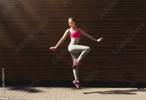 Beautiful sporty young woman posing against brown wall