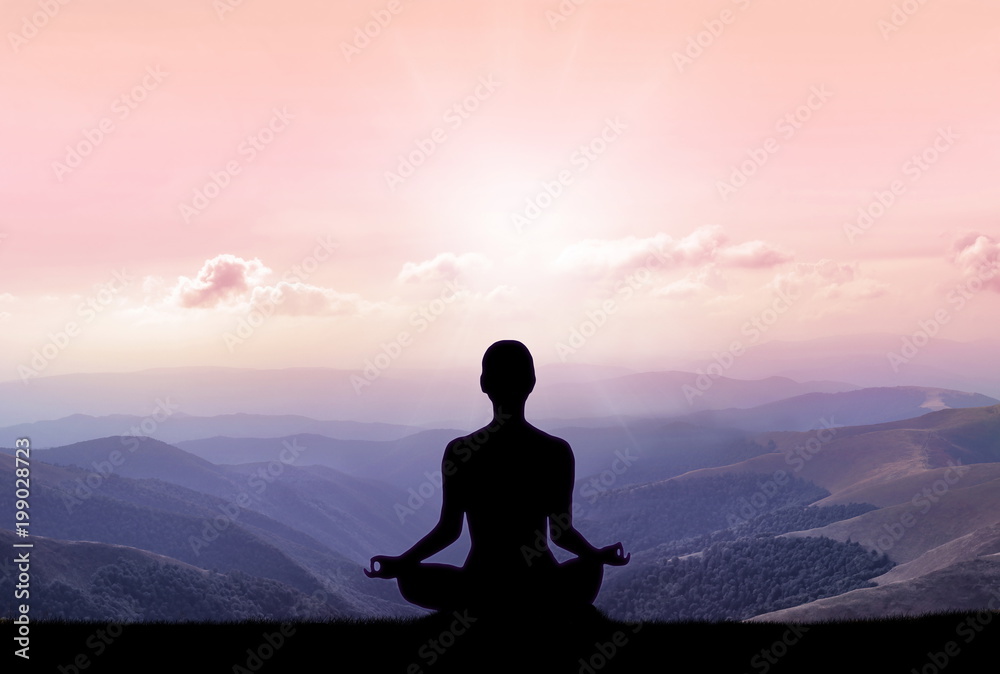 Yoga silhouette on the mountain in sunrays