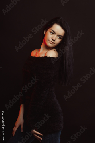 Model test with luxurious lady woman in knitted sweater posing over a black studio background