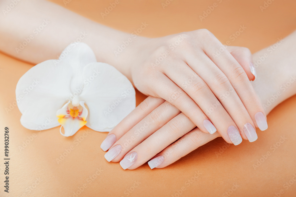 Ombre french manicure with white orchid on orange background. Female hands with white ombre french manicure.