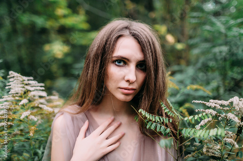 Portrait of beautiful caucasian girl in green leaves. Soft focus