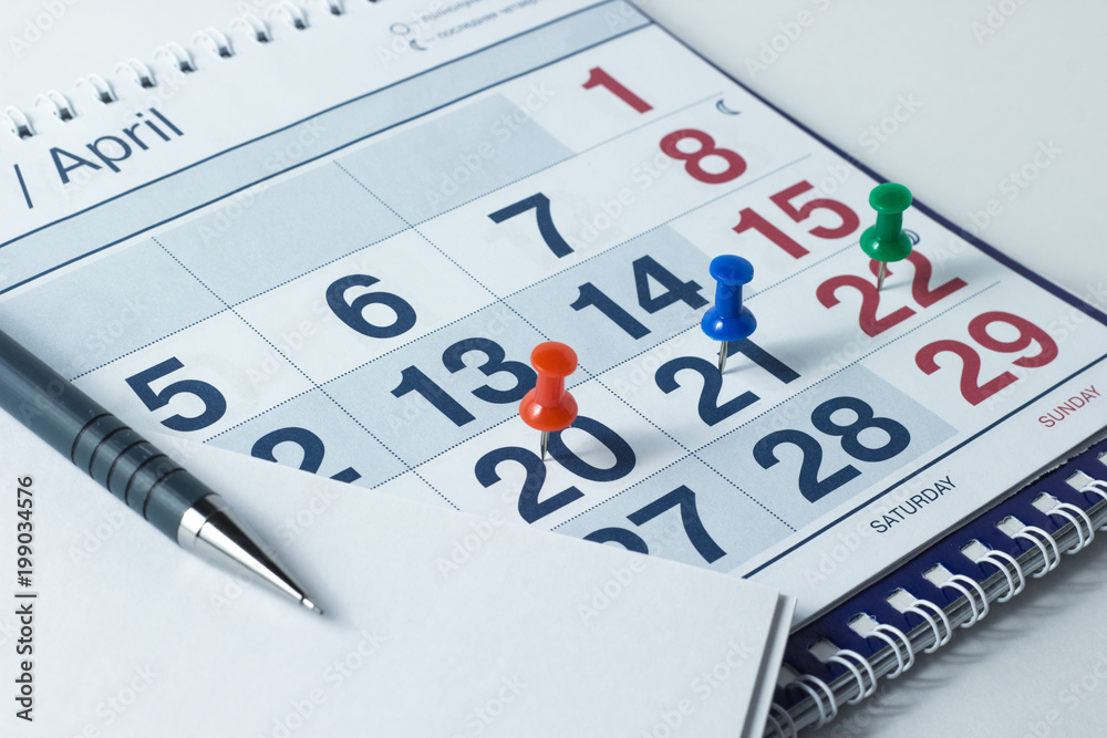 Wall calendar and pen, important days are marked with knops Wall calendar and pen, important days are marked with knops