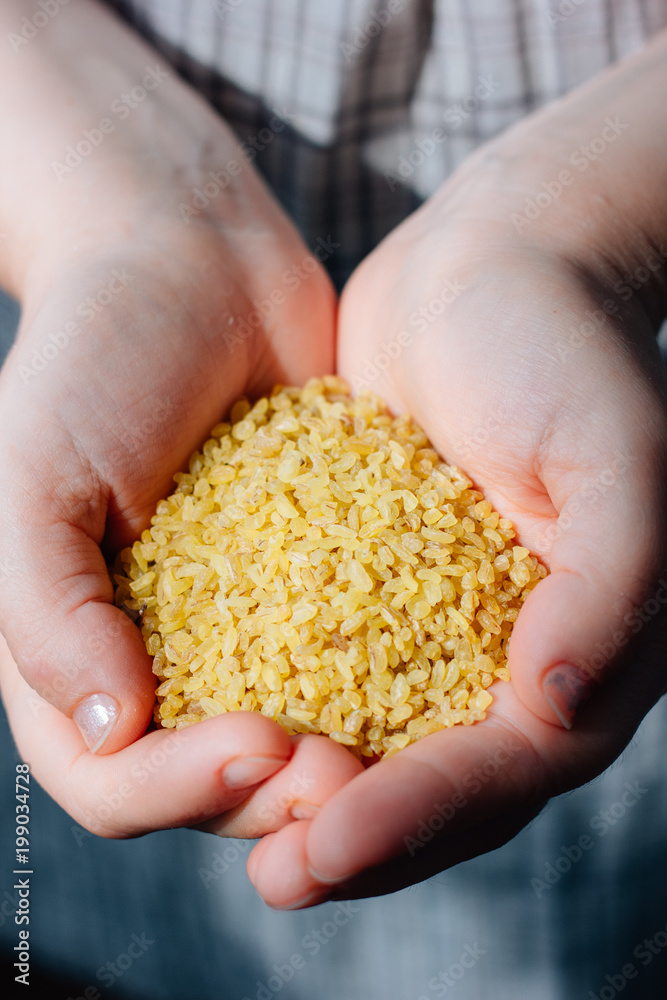 Woman holding natural organic bulgur cereal in hands. Woman holding natural organic bulgur cereal in hands.