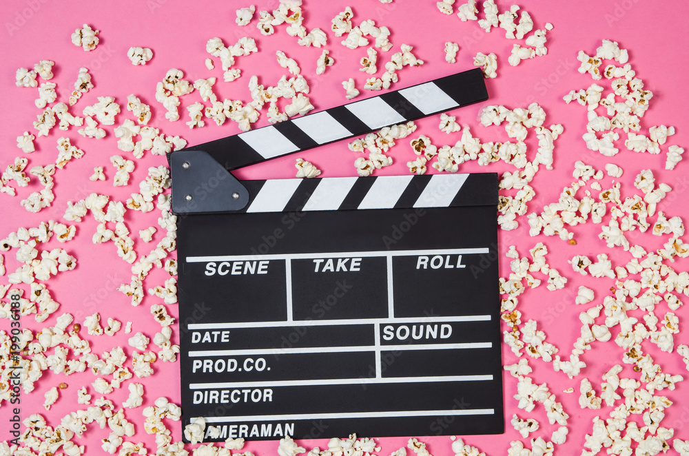 Fresh popcorn and movie clip isolated on pink background top view with copy space around products. Cinematic concept for blogs or design