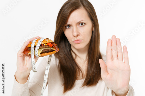 Close up woman holds in hands burger with tailor measuring tape around isolated on white background. Proper nutrition or American classic fast food. Copy space for advertisement. Advertising area.